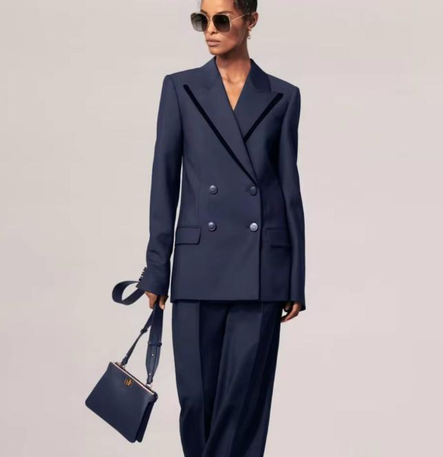 Woman wearing a navy blue double-breasted cotton twill suit with peak lapels and matching tailored trousers.