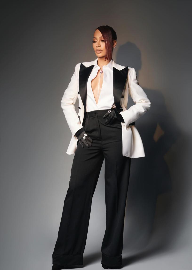 Model wearing a white double-breasted tuxedo jacket with black satin peak lapels and matching black tailored trousers.