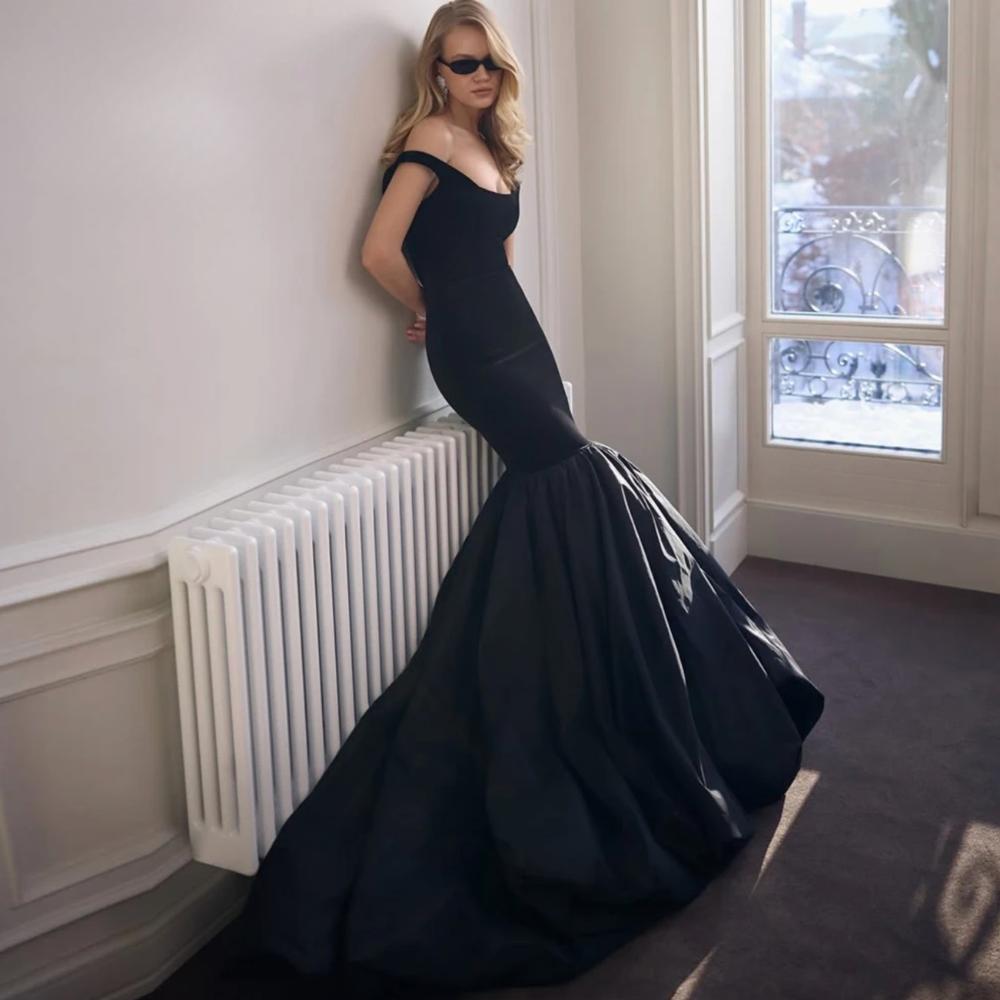 Elegant black satin mermaid gown with a structured square neckline and dramatic flared skirt for formal evening wear.