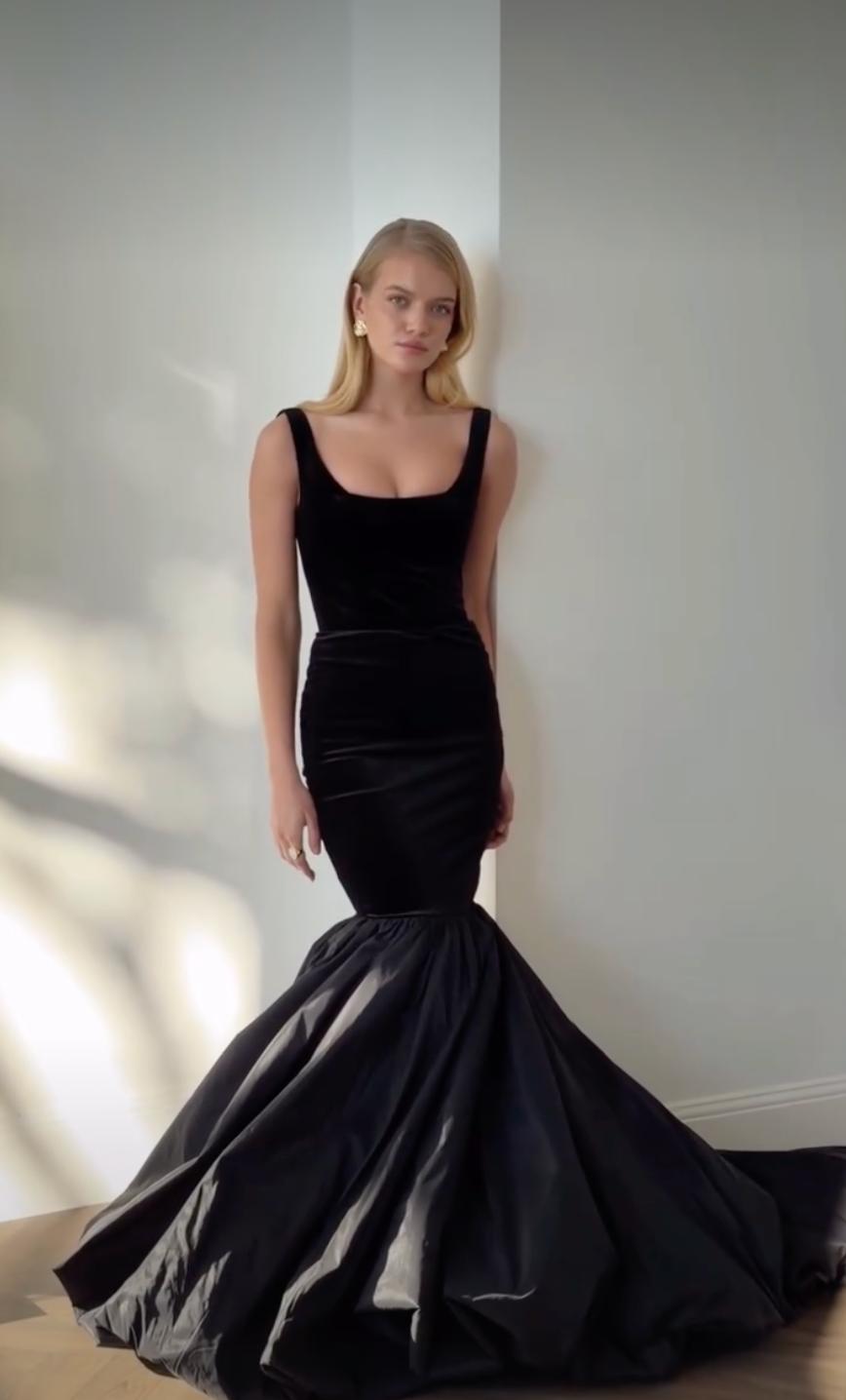 Black velvet mermaid gown with a square neckline and voluminous skirt, featuring a sophisticated, structured silhouette.