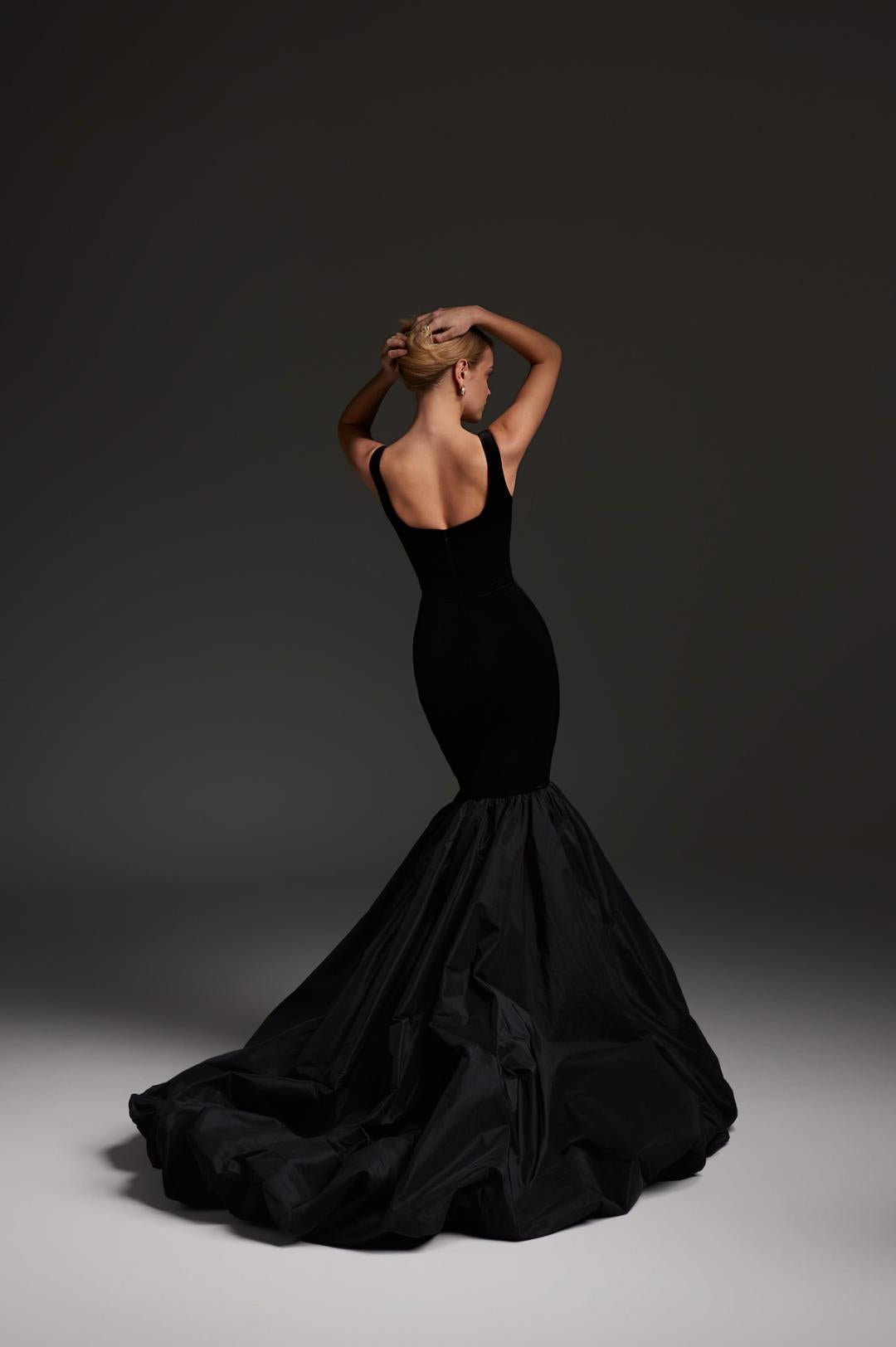 Black velvet mermaid gown with a square neckline and voluminous floor-length skirt, shown from the back.