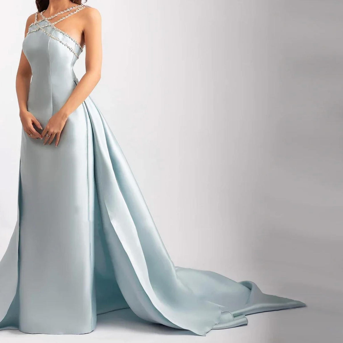 Light blue satin mermaid evening gown with crystal-beaded halter neckline and dramatic detachable overskirt train.