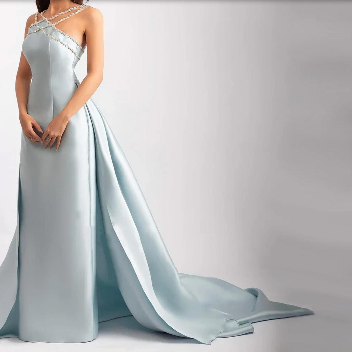 Light blue satin mermaid evening gown with a crystal-beaded halter neckline and a dramatic detachable overskirt train.