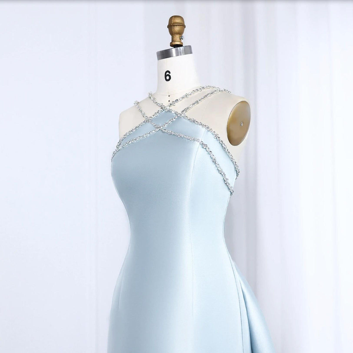 Light blue satin mermaid evening gown featuring a crystal-beaded halter neckline on a dress form.