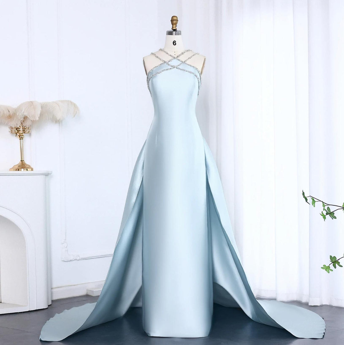 Light blue satin mermaid evening gown with crystal-beaded halter neckline and dramatic detachable overskirt.