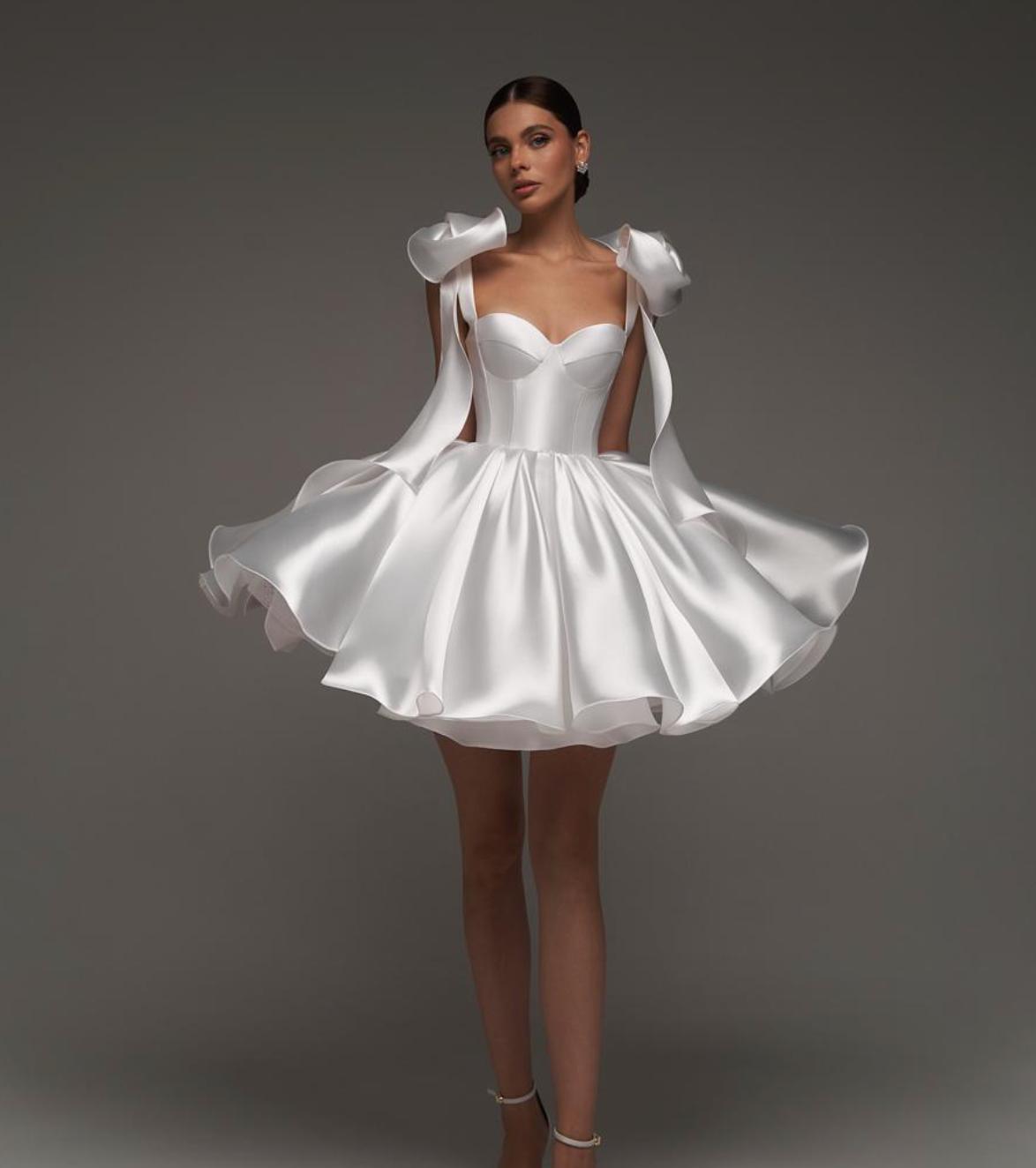 White satin mini ball gown with sweetheart neckline, empire waist, and decorative shoulder bows.