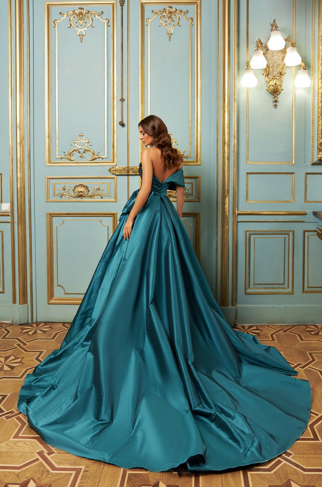 Teal taffeta one-shoulder A-line gown with a backless design, bow V-neckline, and a dramatic floor-length pleated skirt.