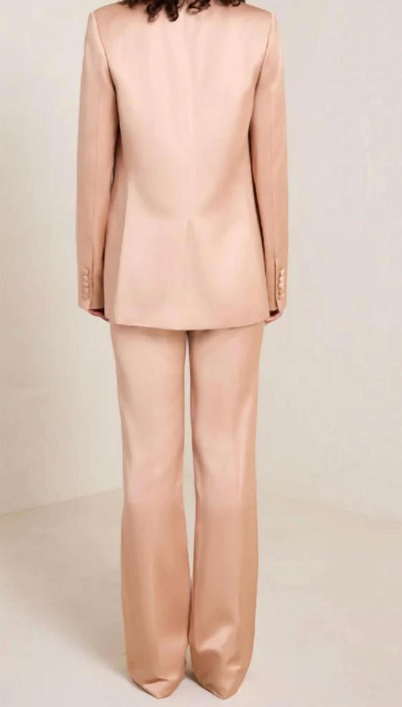 Back view of a sleek, blush pink satin two-piece suit featuring a tailored blazer and matching trousers.