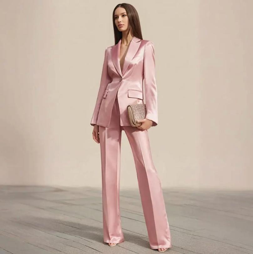 Model wearing a pink satin two-piece office suit with a slim-fit blazer, peak lapels, and matching wide-leg trousers.