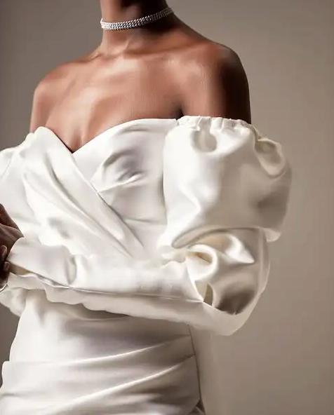 White satin off-the-shoulder mini dress with puff sleeves and a sweetheart neckline for an elegant party look.
