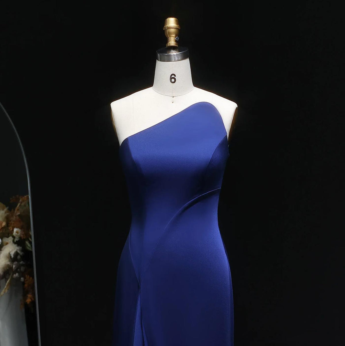 Elegant dark blue mermaid gown in smooth taffeta with a sophisticated one-shoulder, sleeveless silhouette on a mannequin.