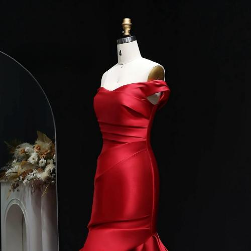 Red satin off-shoulder mermaid evening gown with elegant draping on a mannequin.