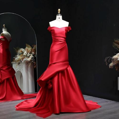 Red satin off-shoulder mermaid evening gown with draped bodice and 3D floral accents on a mannequin.