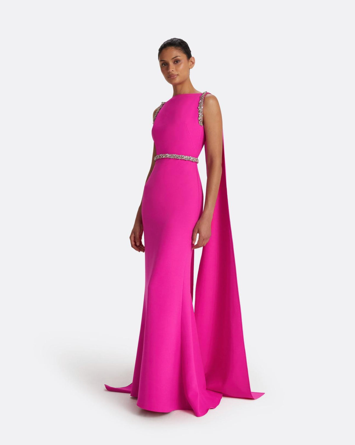 Fuchsia crepe floor-length gown with a dramatic split cape and intricate multi-pastel crystal shoulder and waist detailing.