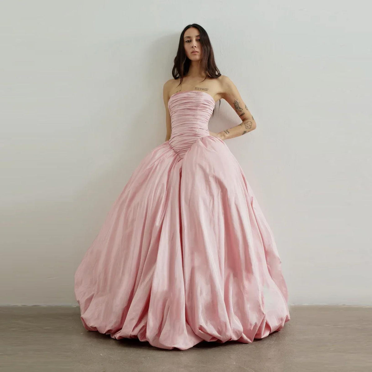Strapless pink taffeta A-line gown with a ruched bodice and voluminous floor-length skirt for formal occasions.