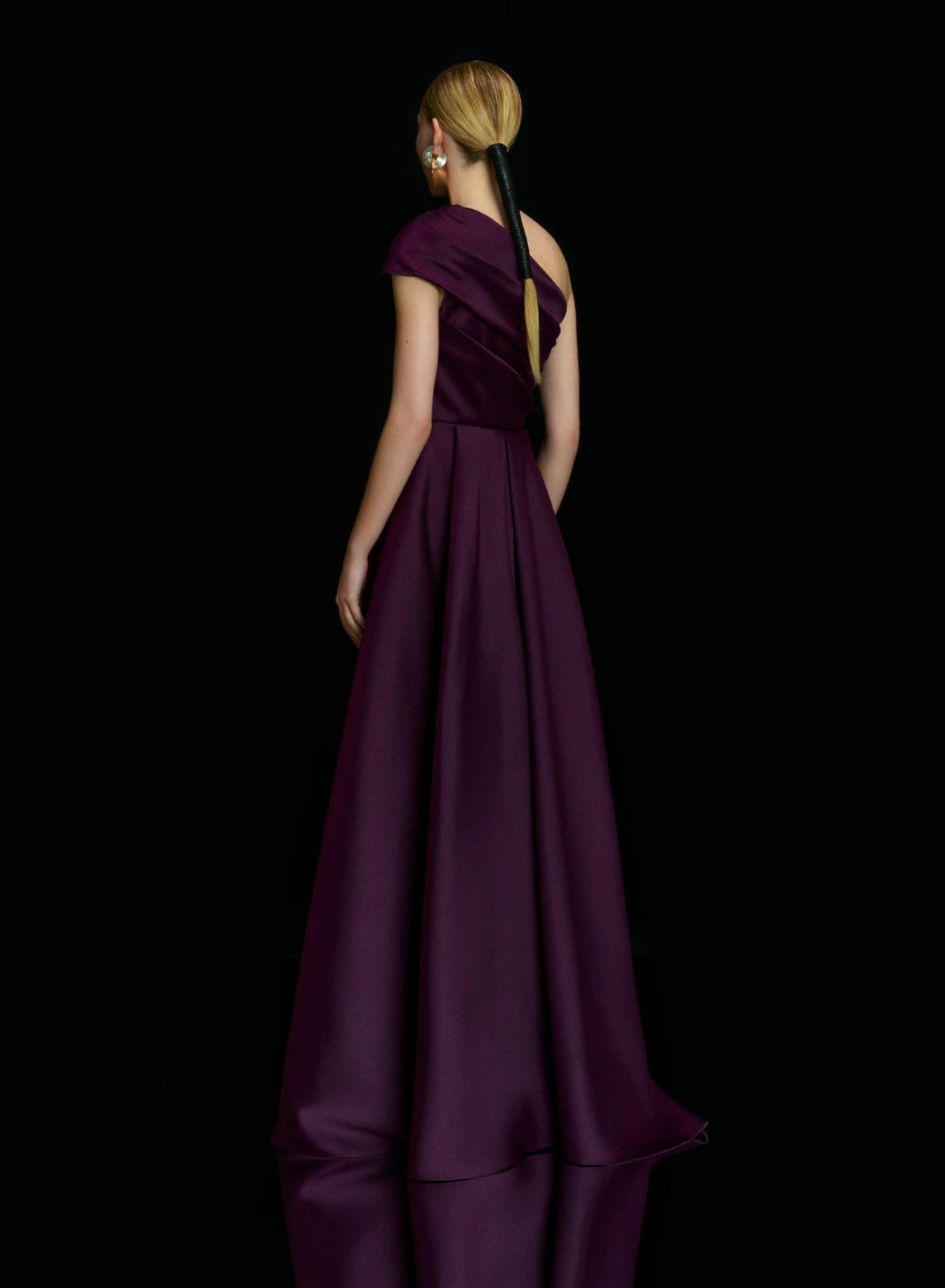 Deep purple satin one-shoulder gown with a fitted waist, pleated A-line skirt, and elegant demi-train.