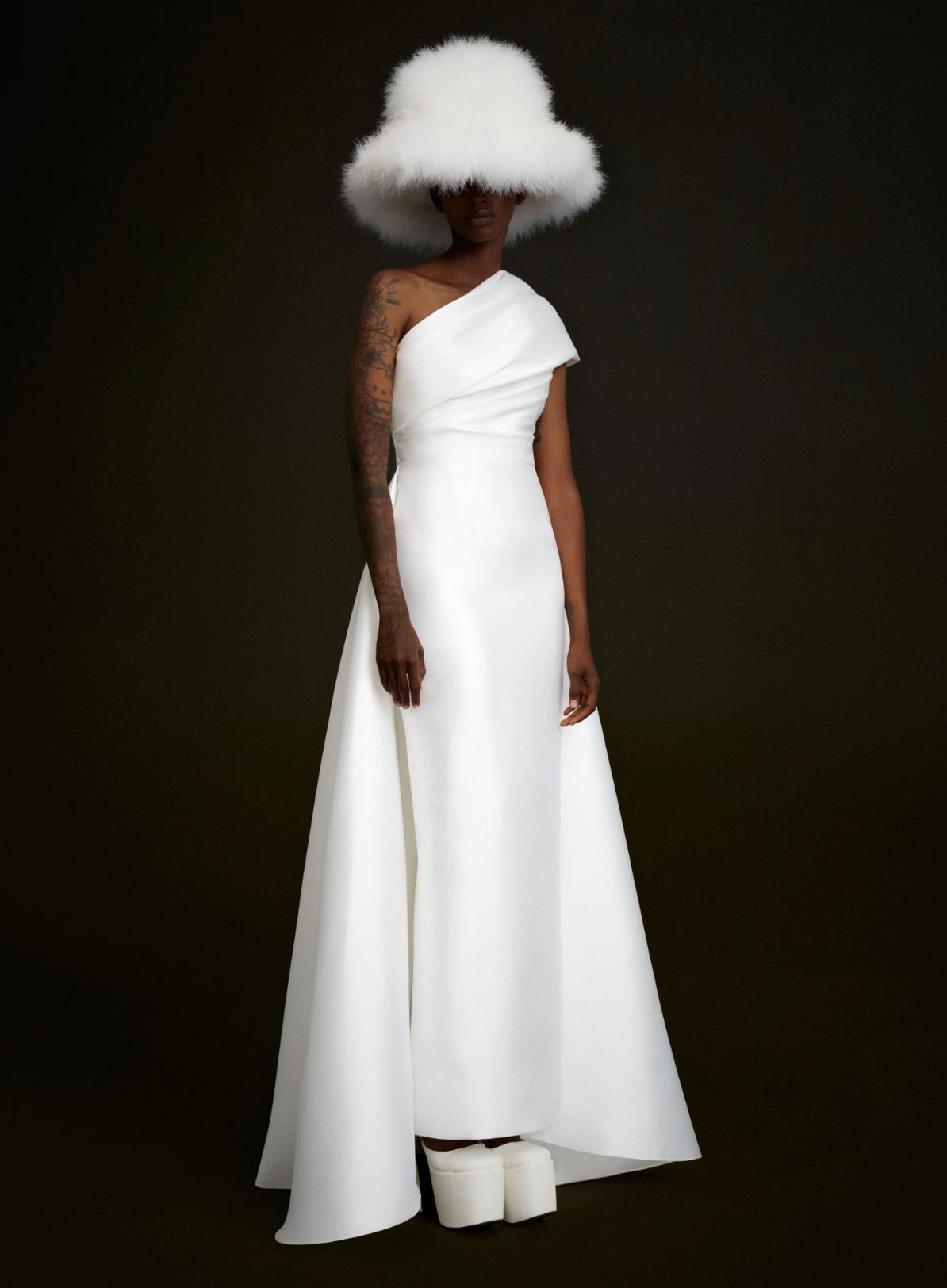 Tallulah white satin one-shoulder gown with draped bodice, A-line skirt, and matching oversized feathered hat.
